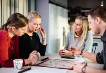 fyra personer sitter och spelar sällskapsspelet alfapet