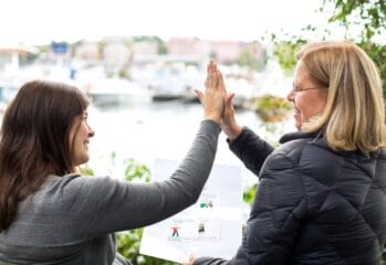 Två personer gör high-five, en av dem håller i ett papper med bildstöd