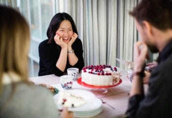 Glada personer sitter runt ett bord med en tårta