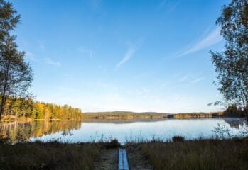 En sjö i solnedgång, det går plankor fram till sjön.