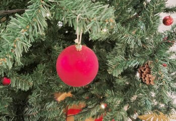 närbild julgran med röd kula, paket under granen