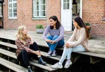 Tre ungdomar sitter på ett trädäck