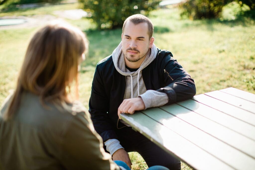Två personer samtalar på en bänk utomhus