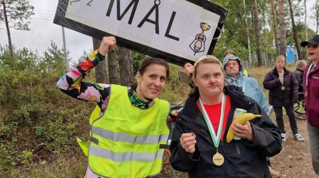 Deltagare och funktionnär vid målgången med skylt med texten mål