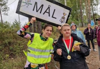 Deltagare och funktionnär vid målgången med skylt med texten mål