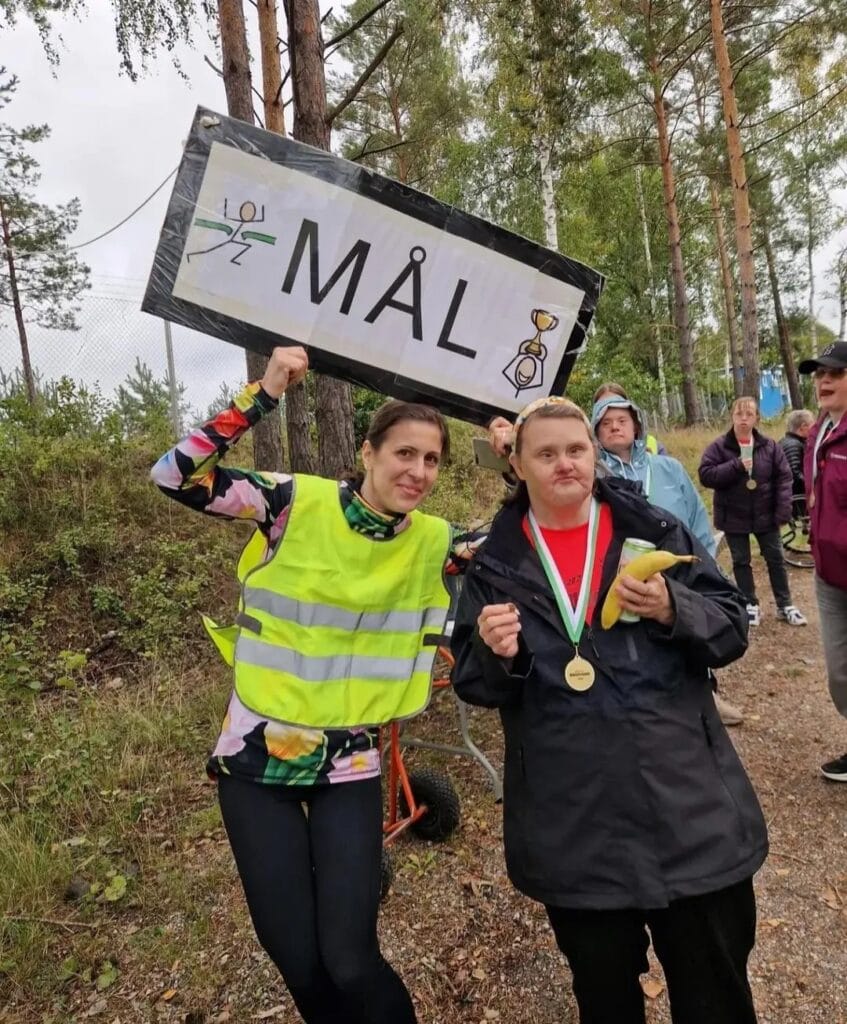 Deltagare och funktionnär vid målgången med skylt med texten mål 