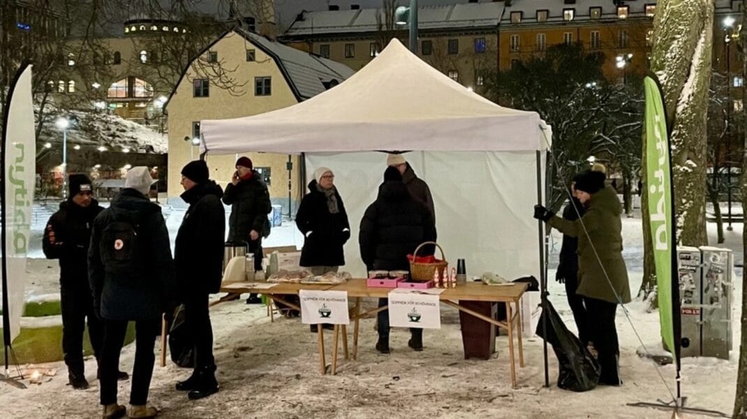 Nytida medarbetare står under vitt tält på torg och delar ut soppa
