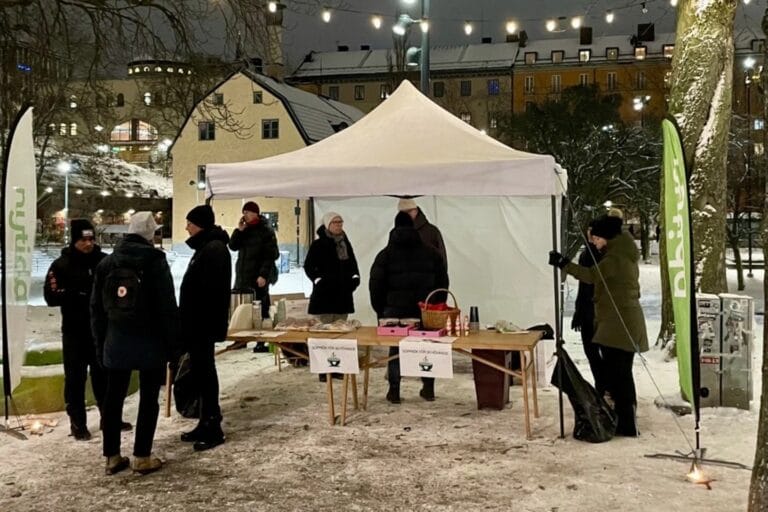 Nytida medarbetare står under vitt tält på torg och delar ut soppa