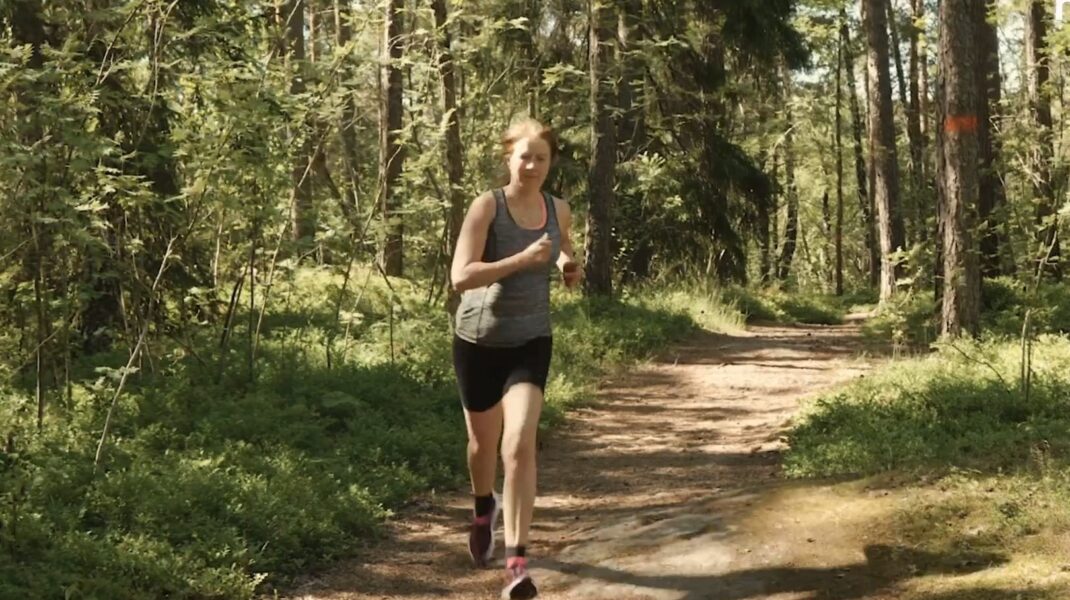 Elisabeth som står i motionsspåret i skogen